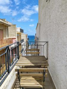 una panca di legno seduta su un balcone con vista sull'oceano di Appartamenti Blu Mare a Castellammare del Golfo