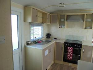 Il comprend une petite cuisine équipée d'un évier et d'une cuisinière. dans l'établissement Sapphire 8 Berth panel heated Towervans, à Sutton-on-Sea