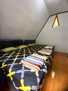 a bed with blankets and pillows on it in a room at Penginapan segitiga pangalengan in Riunggunung