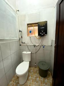 Baño pequeño con aseo y cubo verde en Penginapan segitiga pangalengan, en Riunggunung