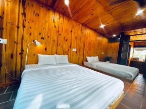 two beds in a room with wooden walls at Lam Vien Garden Villa - Homestay Da Lat in Da Lat