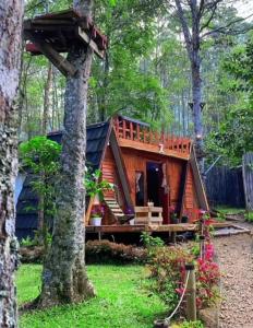 una cabaña de madera en el bosque con un árbol en Penginapan segitiga pangalengan, en Riunggunung