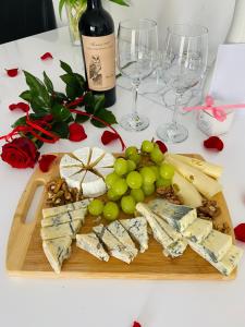 a cutting board with cheese and grapes and wine glasses at Kaliny Apartamenty Katowice Chorzów in Chorzów