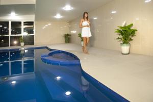 a woman in a white dress standing next to a swimming pool at CBD Executive Apartments in Rockhampton