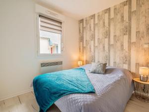 um quarto com uma cama com um cobertor azul e uma janela em Apartment Les Caps Horniers-2 by Interhome em Pleurtuit