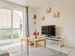 uma sala de estar com uma televisão e uma mesa em Apartment Les Caps Horniers-2 by Interhome em Pleurtuit