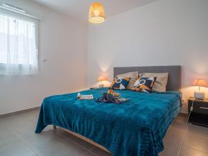 een slaapkamer met een groot bed en een blauwe deken bij Apartment Clos Isabelle by Interhome in Canet-en-Roussillon
