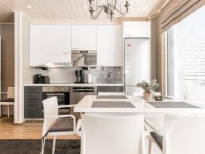 eine Küche mit weißen Schränken und einem Tisch und Stühlen in der Unterkunft Holiday Home Golfarinkunnas 7b by Interhome in Jämsä
