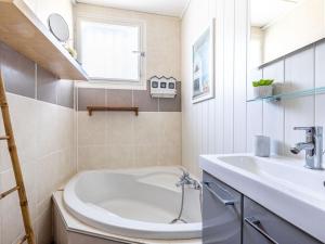 uma casa de banho com uma banheira branca e um lavatório. em Holiday Home Mayne Pauvre by Interhome em Carcans
