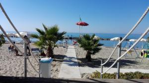 uma praia arenosa com palmeiras e um caminho em A Casa Scipione em Formia