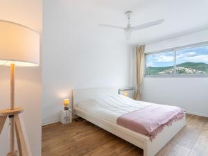 a white bedroom with a bed and a window at Apartment Le Grand Large-2 by Interhome in Hyères