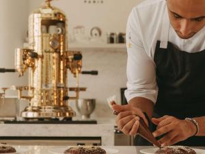 un homme dans une cuisine préparant de la nourriture sur une assiette dans l'établissement Raffles Al Areen Palace Bahrain, à Manama