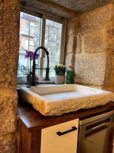 Un fregadero de cocina con una pared de piedra y una ventana. en Casa centro histórico Vilanova, en Villanueva de Arosa