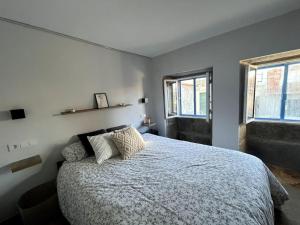 Un dormitorio con una cama grande y dos ventanas. en Casa centro histórico Vilanova, en Villanueva de Arosa