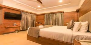 Hotel Airport Sinon By Dream Laxmi في نيودلهي: غرفة نوم بسرير كبير وتلفزيون