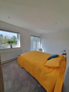 - une chambre avec un grand lit et une couverture jaune dans l'établissement Broxbourne apartment (2 bed), à Broxbourne