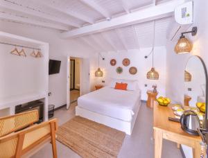 a white bedroom with a white bed and a table at Caliza Alaçatı in Alaçatı