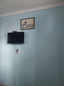 uma parede com uma fotografia e uma televisão em S R Homestay em Chari