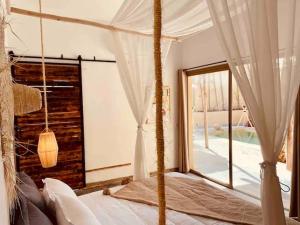 a bedroom with a canopy bed with a window at Superbe Villa piscine chauffée bali Marrakech in Marrakech