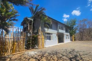 una casa con una valla y una palmera en Villa Ballena Art Project, en La Cruz