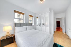 um quarto branco com uma cama grande e um candeeiro em Modern 2Bed 2Bath Apartment Secure Gated FREE Parking Tower Bridge by London Bridge - Perfect For Long Stays em Londres