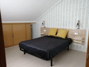 a bedroom with a bed with two yellow pillows at La buhardillita in Laredo