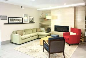 een woonkamer met een bank en een rode stoel bij Wingate by Wyndham Matthews, NC in Matthews