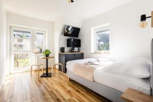 biała sypialnia z łóżkiem i 2 oknami w obiekcie Apartamenty ZakoCHata Zakopane w Zakopanem