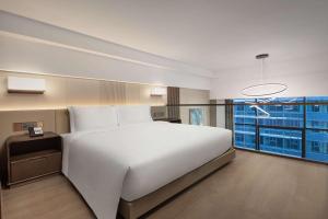 een slaapkamer met een groot wit bed en een groot raam bij Wyndham Dalian Jinpu in Dalian