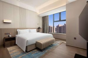 1 dormitorio con cama blanca y ventana grande en Wyndham Dalian Jinpu, en Dalian