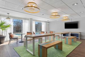 a conference room with tables and chairs and a flat screen tv at Spark By Hilton Greensboro in Greensboro