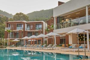 ein Hotel mit einem Pool mit Stühlen und Sonnenschirmen in der Unterkunft The Club Cala San Miguel Hotel Ibiza, Curio Collection by Hilton, Adults only in Puerto de San Miguel