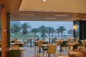 un restaurante con mesas y sillas y vistas al océano en The Club Cala San Miguel Hotel Ibiza, Curio Collection by Hilton, Adults only en Puerto de San Miguel