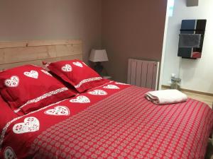 - un lit rouge avec une couette rouge et blanche dans l'établissement LE DOMAINE DE LA LOUVE BLANCHE, à Le Mont-Dore