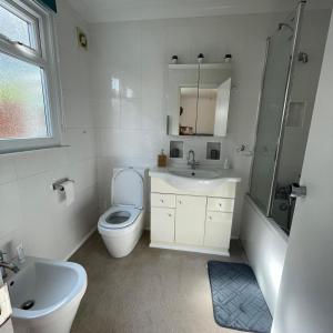 a white bathroom with a toilet and a sink at Charming 3-Bed Home in Halsted in Halstead