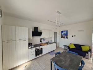 Appartamento MaRi في فانو: مطبخ مع دواليب بيضاء وطاولة في الغرفة
