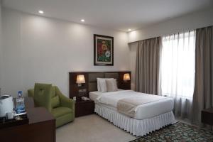 um quarto de hotel com uma cama e uma cadeira verde em The Alcor Hotel em Jamshedpur