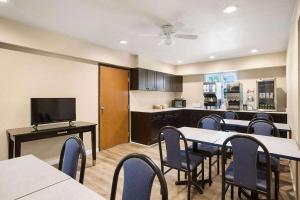 a dining room with tables and chairs and a kitchen at Days Inn by Wyndham Mackinaw City - Bridgeview Area in Mackinaw City