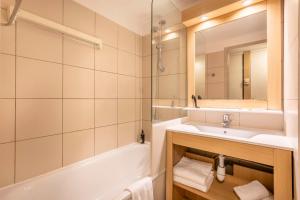 a bathroom with a sink and a tub and a mirror at Zenitude Hôtel Résidences - Marseille Prado Plage in Marseille