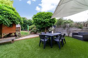 a table and chairs on the grass with an umbrella at Comfy 3BR grd floor flat wprivate garden, NE in London