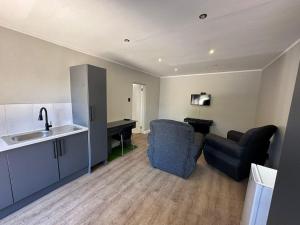 eine Küche und ein Wohnzimmer mit 2 Stühlen und einem Waschbecken in der Unterkunft Conti-INN Guesthouse in Queenstown