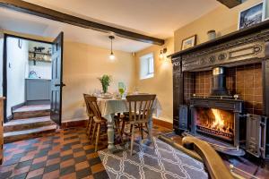 uma sala de jantar com lareira, mesa e cadeiras em Finest Retreats - Spring Cottage em Endon