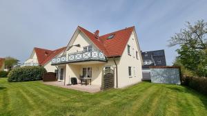 a white house with a balcony on top of a yard at Hoppenberg 7 EG links in Zingst