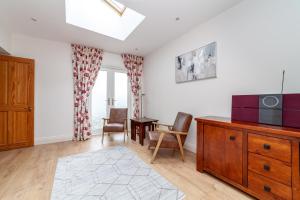 a living room with a tv and a table and chairs at Comfy 3BR grd floor flat wprivate garden, NE in London