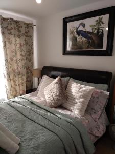 a bed with pillows and a picture of a bird at House Rose 1 in Prescot