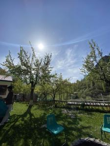 zwei Stühle in einem Garten mit einem Baum und der Sonne in der Unterkunft Rainbow Resort Kachura in Karatschi