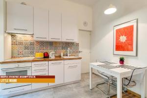 a kitchen with white cabinets and a white table at Little Americas Opera Apts in Budapest