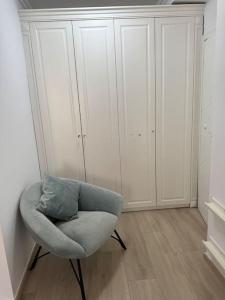 een witte kamer met een stoel en een aantal kasten bij Leos Apartment in Tirana