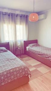 een slaapkamer met 2 bedden en een hanglamp bij Leos Apartment in Tirana