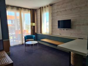 een kamer met een tv en een stoel en een tafel bij Hotel Cap D'Ambre in La Barre-de-Monts
